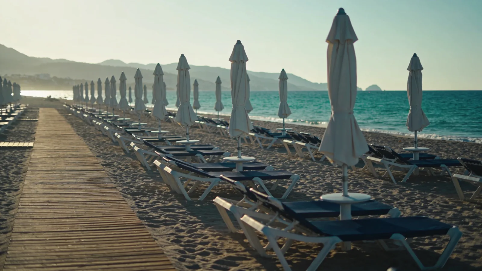 Sun loungers and parasols on a wide Marbella beach with a wooden boardwalk and the Mediterranean behind